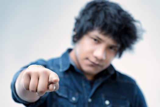 young man in the blue denim shirt extends a pointing finger, his hair unkempt, as he gives a challenging look