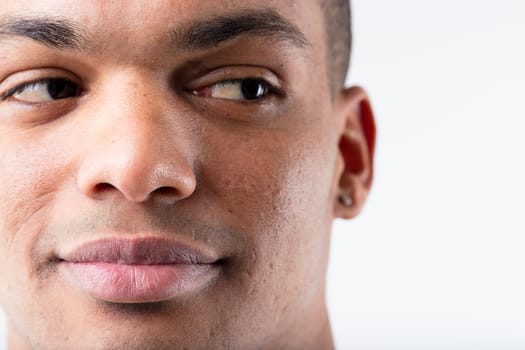 Close-up portrait of a young, smiling black man, cleverly glancing sideways towards the copyspace. His eyes suggest interest or approval. Positive
