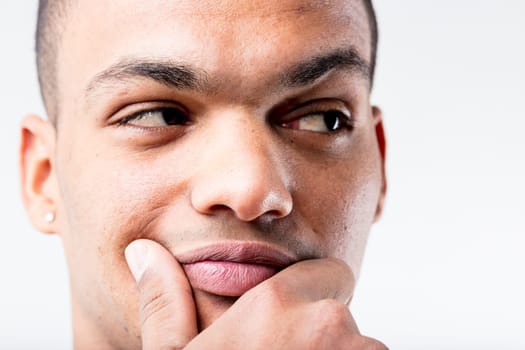 A black man's close-up portrait. He's either pondering a lucrative idea or doubting someone's integrity, as he pensively rubs his lower face