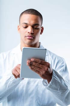 Lab technician with tablet. Black man in white coat is an expert researcher, scientist, or lab tech. He uses his device to monitor analysis results, data, and connects online