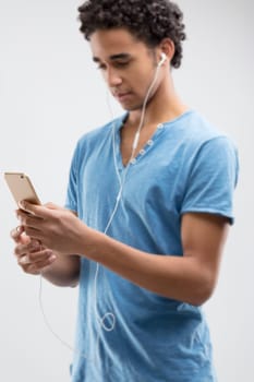 Young man in blue appears captivated by his phone's content, perhaps engrossed in a melody or article