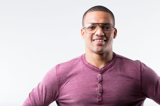 Portrait of a joyful young black man, stylishly donning metallic-framed glasses. Once viewed as nerdy in the 80s and 90s, now deemed cool. Fashion's a curious thing