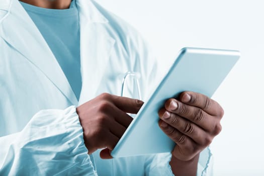 Black man, a laboratory expert in white coat, uses tablet for analyzing data, collaborating with organizations through internet. He's a proficient researcher or lab technician