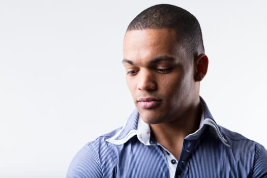 A well-off black man, part of high-earning middle class, wears a blue polo-style shirt. He appears thoughtful and perhaps worried, troubled, sad, serious. Life's hardships are universal