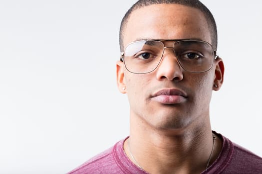 Portrait of a serious, expressionless young black man wearing metallic-framed glasses. Considered nerdy in the 80s and 90s, now they're cool. Fashion is strange