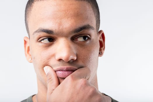 Close-up of a black man thinking hard. He could have a brilliant idea for enrichment, or suspect a scam, all while touching his lower face