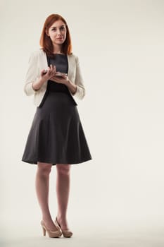 Elegance in the workplace: a professional woman stands with her smartphone, embodying grace and connectivity