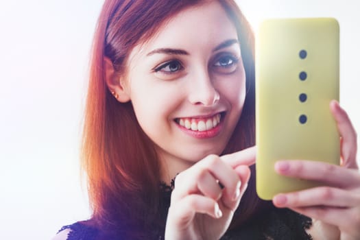 In a moment of digital connection, the woman's smile and the smartphone screen share a luminous bond