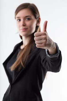 thumbs up! in focus in foreground, young businesswoman blurred in background. Agree and support your choice. Way to go!