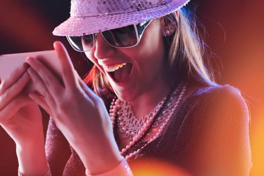 Engulfed in radiant hues, a delighted woman shares a hearty laugh while engaging with her smartphone