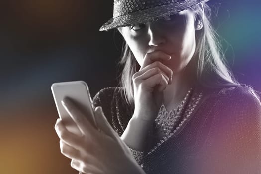 Engrossed in her device, her finger thoughtfully at her lips, a modern-day enigma