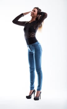 Beautiful young lady yawns mockingly, accentuating her perfect physique. Slim and toned, with long hair, she's clad in a tight black lace top, skinny jeans, and towering heels