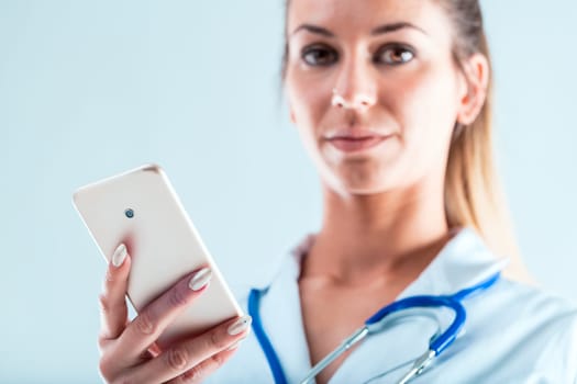 Close-up of a smartphone held by a doctor's hand with perfect manicure. She suggests you do it online, using your mobile. Many benefits with less hassle of commuting, if you adapt to this change