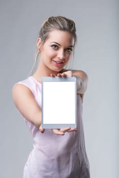 Confident woman presents a tablet with a blank screen, inviting interaction