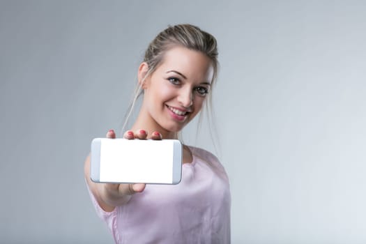 Smiling woman presents a smartphone, highlighting modern connectivity