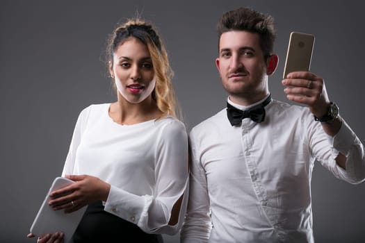 Elegantly dressed woman focuses on a tablet, man checks his phone