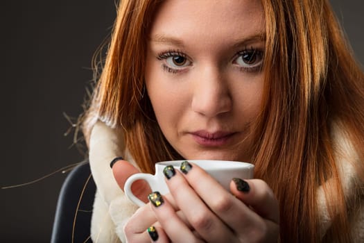 Intimate close-up of a woman with red hair savoring a cup of comfort
