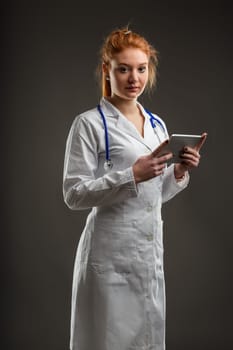 Confident female doctor with striking hair color uses a tablet, symbolizing the intersection of technology and care