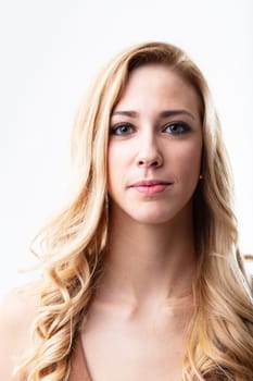 Front-facing portrait of a confident blonde woman. Her silent smile shines through her eyes. White background adds to her radiance
