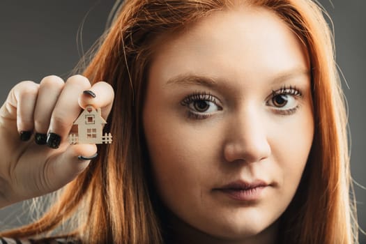 contemplative woman showcases a small home, pondering the concept of shelter