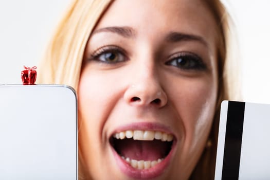 Online shopping satisfaction with a blonde woman, smartphone, credit card, gift. Convenience and speed in the digital sphere