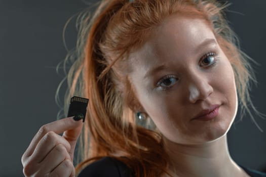 Young tech professional showcases an SD card, a staple in data storage and digital innovation