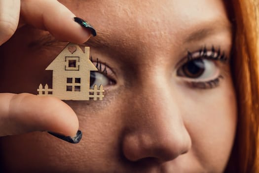 Close-up of a woman's eye through the frame of a tiny house, pondering ownership