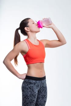 At the gym, a woman hydrates, her muscular arm on display, underscoring the importance of drinking water in achieving physical fitness