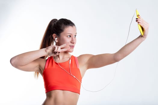 In her colorful sports attire, an Eastern-featured woman clicks a celebratory selfie at the gym, capturing her fitness journey and aesthetic appeal