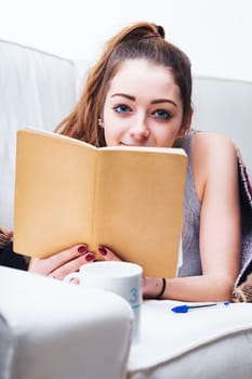 Engrossed in her writing, she lies comfortably on the sofa, her casual attire suggesting a laid-back day at home