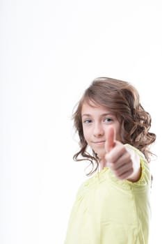 In focus on a white background, a curly-haired girl shows a blurred thumbs up, signifying positivity, optimism, and collaboration. Wearing a green shirt, she smiles with pride
