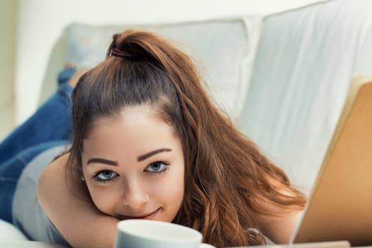Resting her head on her arms, she offers a smile full of charm, a break perhaps from reading or writing