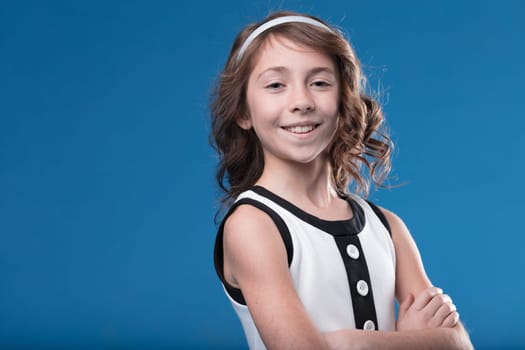Formal portrait of a smiling girl in black and white outfit against blue backdrop, reminiscent of school albums