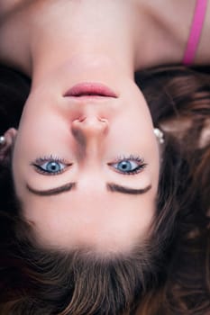 The woman's upside-down perspective adds a playful twist to her relaxed demeanor, framed by cascading waves of hair