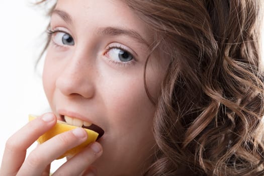 Girl with curls bites into a lemon, experiencing its zesty vitality, symbolic of health