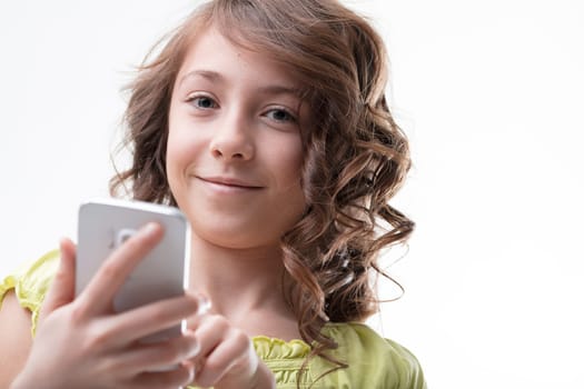 A curly-haired girl in green confidently and adeptly uses a smartphone, symbolizing digital natives