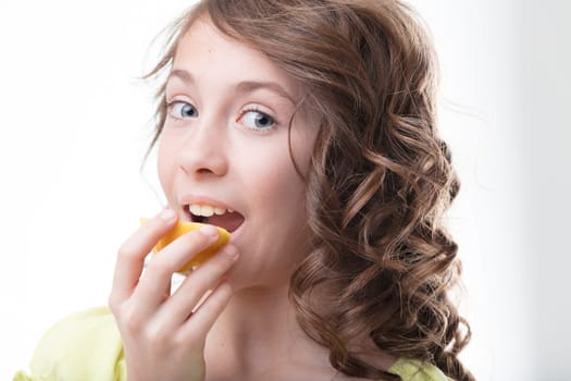 Enjoying the sour-sweet vitality of a fresh lemon, a girl embodies healthy eating habits