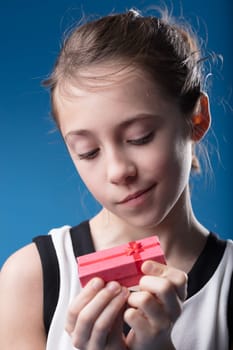 Close-up of an elegant girl with blue eyes, pondering over a small red gift