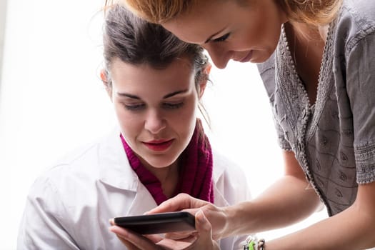 Two women engage with a smartphone, one guiding the other through new technology