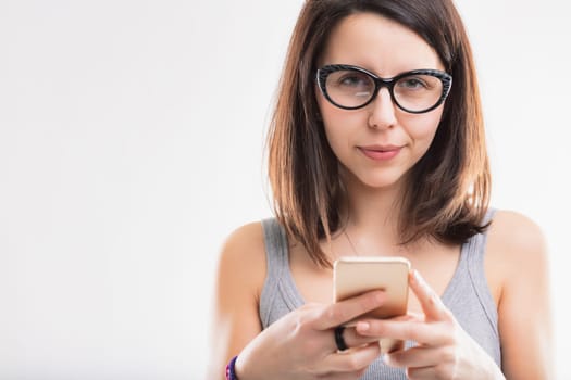 Focused woman in glasses types on her smartphone, her attention captured by the screen
