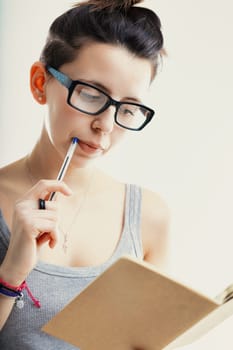 Engrossed in her studies, the woman exhibits focus and concentration, pen in mouth