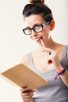 Deep in contemplation, she holds her notebook and pen, a portrait of intellectual engagement