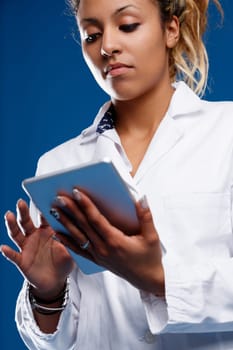 Expert brown-skinned woman using a tablet for big data analysis. Specialized in statistics, she doesn't fall for superficial beliefs supports science