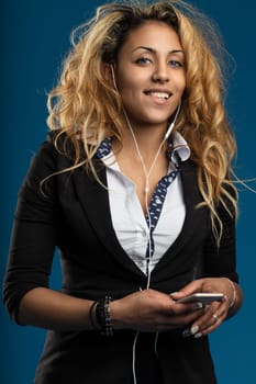 Contemporary professional with earphones, her smart attire and smartphone suggest seamless multitasking