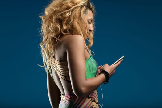 Her attention to the phone contrasts with the wild patterns of her fashionable attire