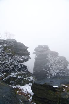 On the large Zschirnstein in fog. Rock covered with snow. Viewpoint during a hike. From the nature park in the Elbe Sandstone Mountains. Landscape in Germany