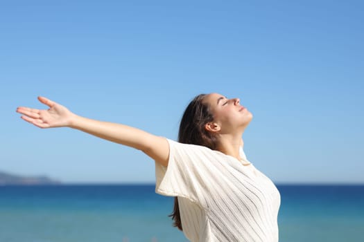 Woman outstretching arms and breathing fresh air on the beach