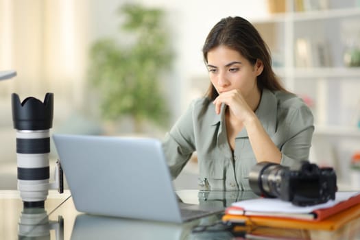 Worried photographer working checking laptop sitting at home