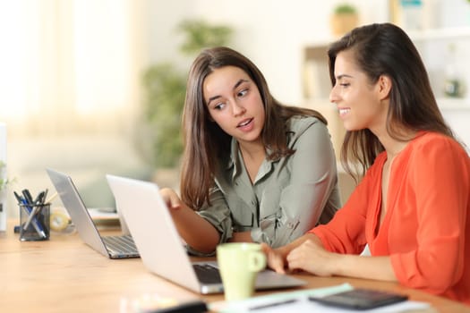 Two tele workers talking about work checking laptop content at home