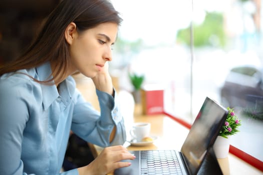 Elegant woman in a coffee shop working using tablet or laptop